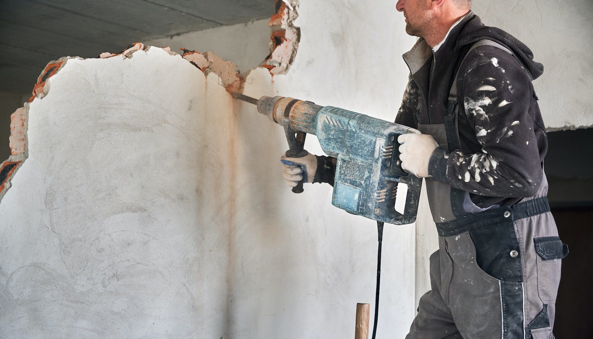 Cropped view worker with perforator during demolition wall.
